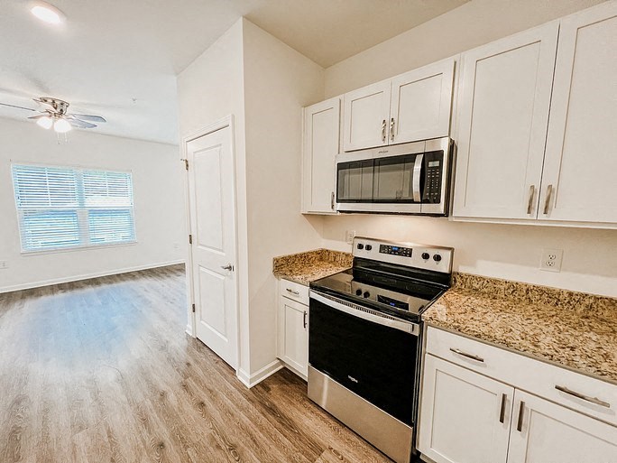 a kitchen with white cabinets and a stove and a microwave