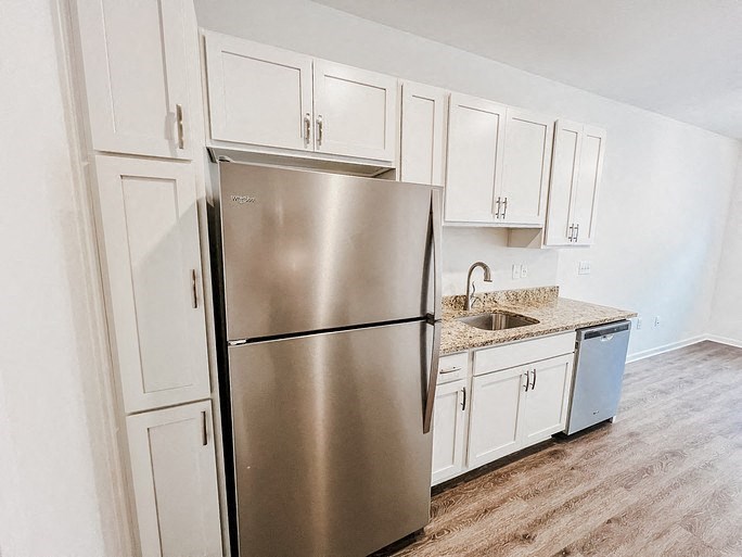 A kitchen with a stainless steel refrigerator and white cabinets.