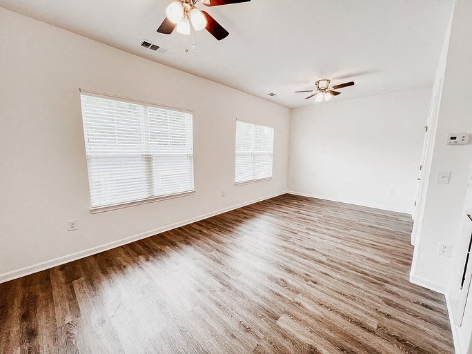 an empty living room with wood floors and a ceiling fan