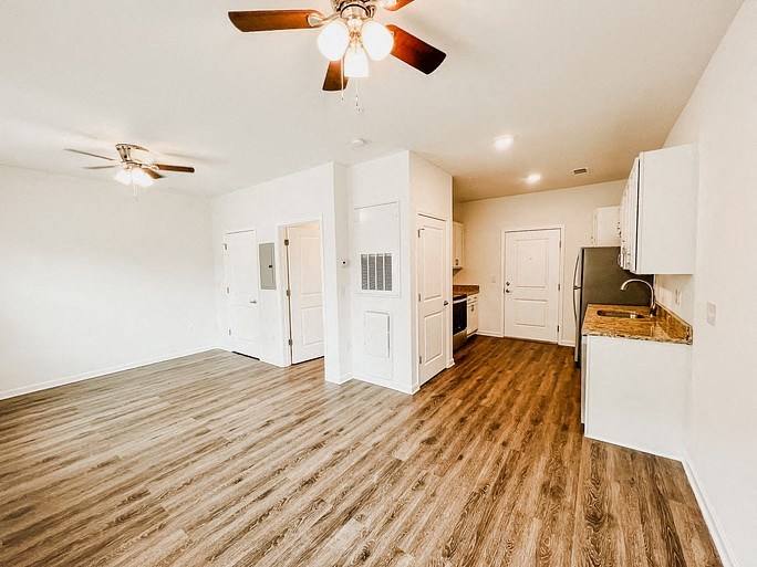 A kitchen with a wood floor and white walls.
