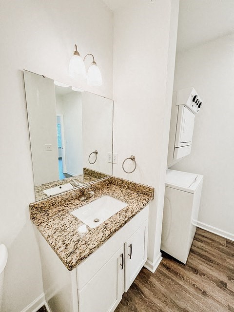 A bathroom with a granite countertop and a white washing machine.