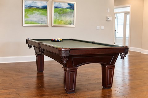 A pool table in a room with two paintings on the wall.