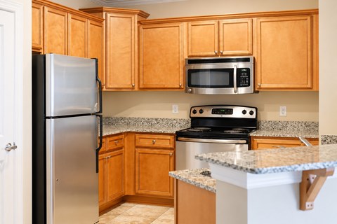 A kitchen with wooden cabinets and a stainless steel refrigerator.