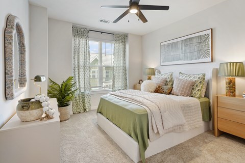 A bedroom with a bed, nightstand, and a ceiling fan.