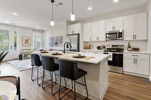 A kitchen with white cabinets and a large island with four chairs.