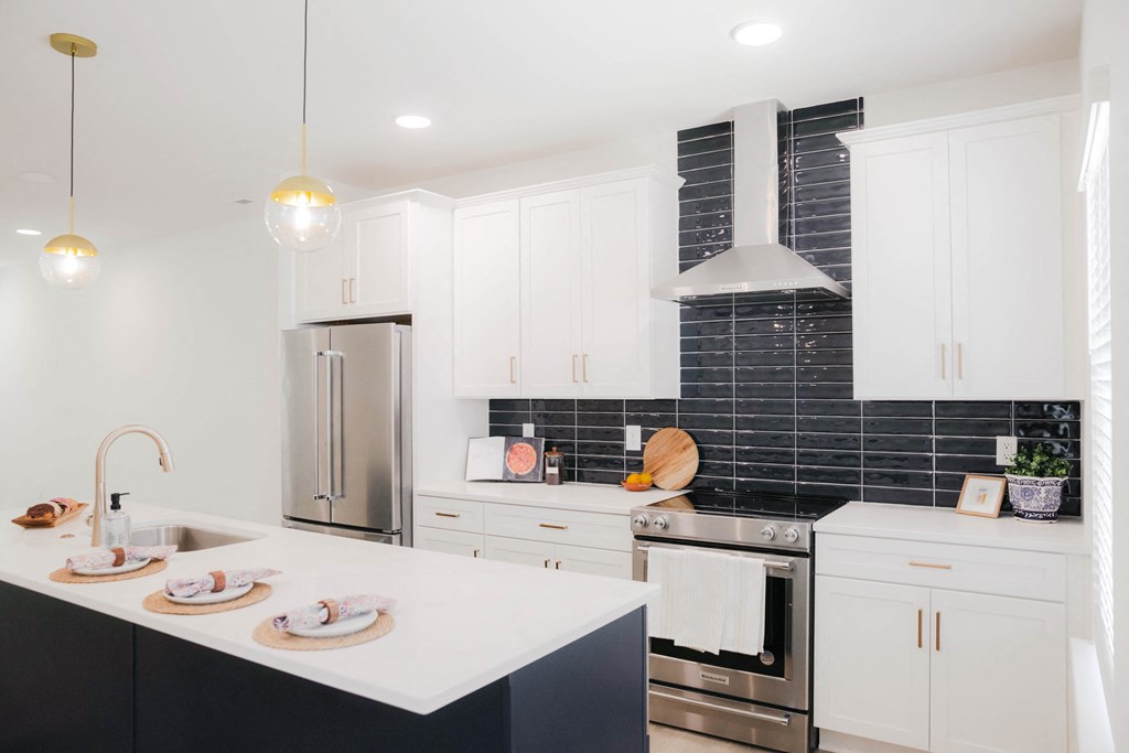 a white and black kitchen with stainless steel appliances and white countertops