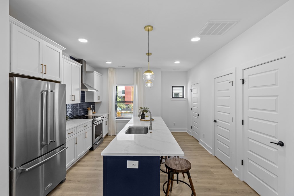 A modern kitchen with white cabinets and a blue island.