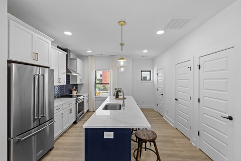 A modern kitchen with white cabinets and a blue island.