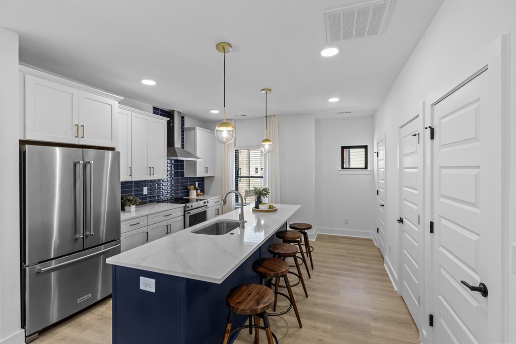A modern kitchen with a blue island and stainless steel appliances.