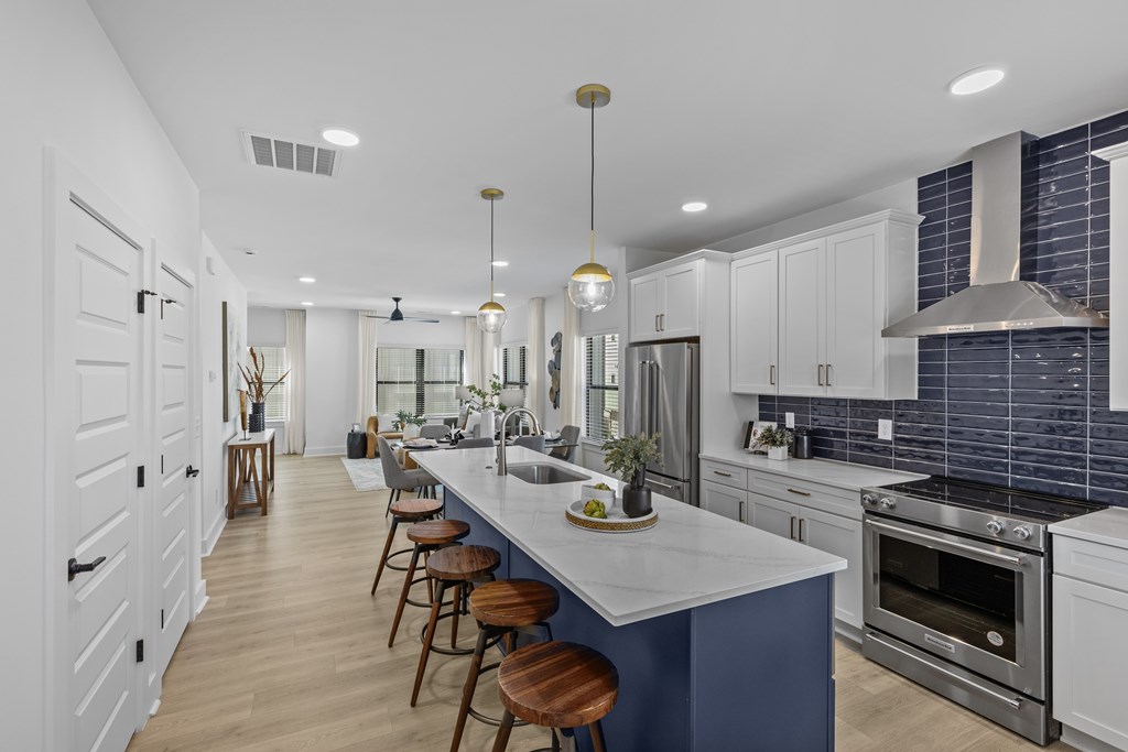 A kitchen with white cabinets and a blue island.