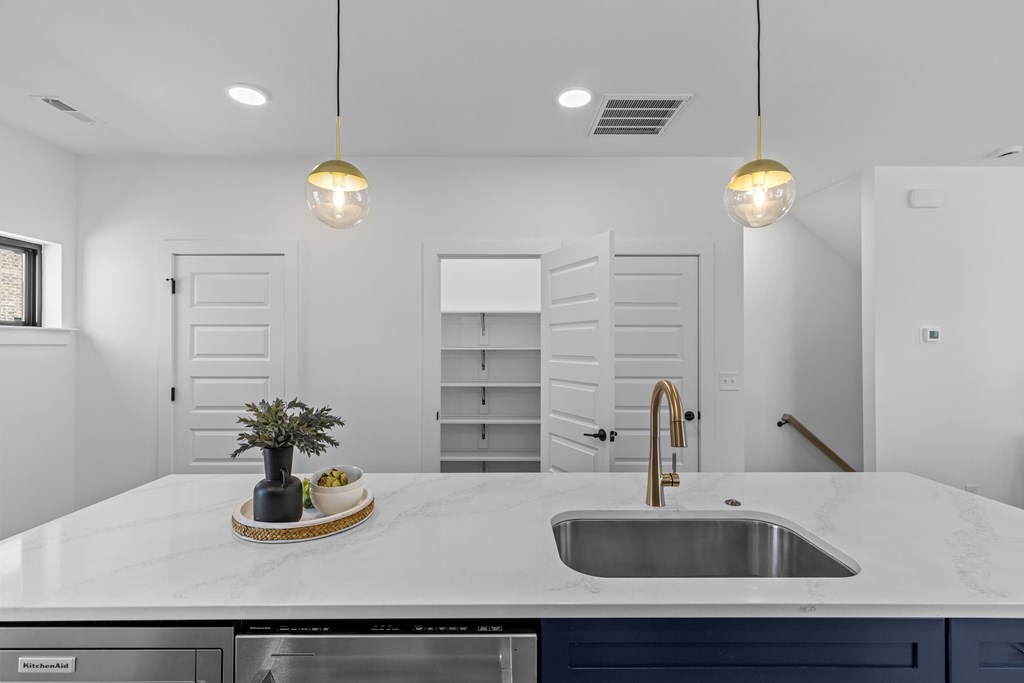 A kitchen with a marble countertop and a stainless steel sink.