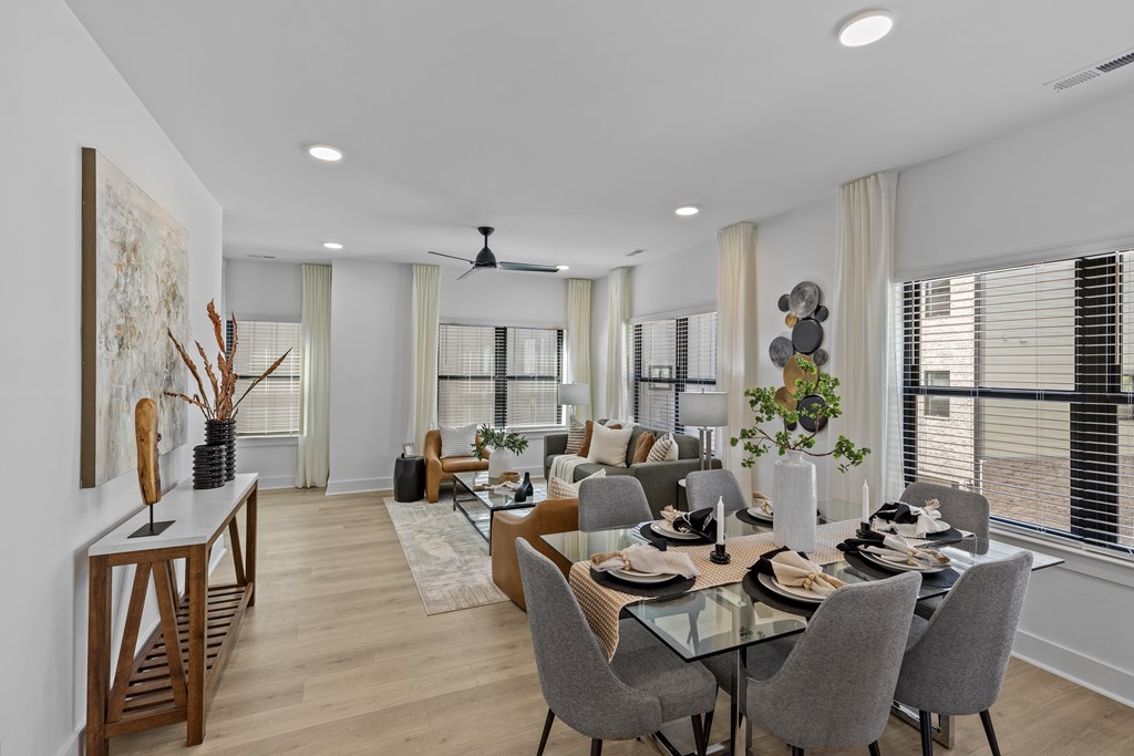 A modern dining room with a glass table and grey chairs.