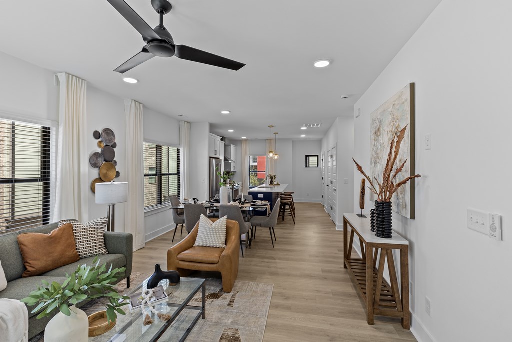 A modern living room with a grey sofa, a wooden coffee table, and a glass top table with a vase on it.