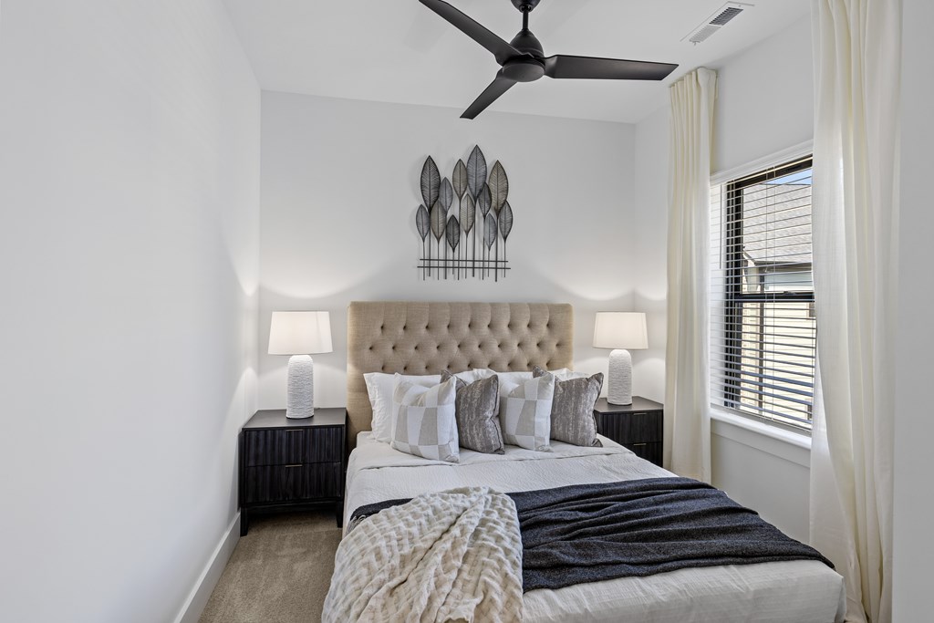 A bedroom with a large bed and a ceiling fan.