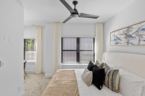 A bedroom with a large bed and a ceiling fan.