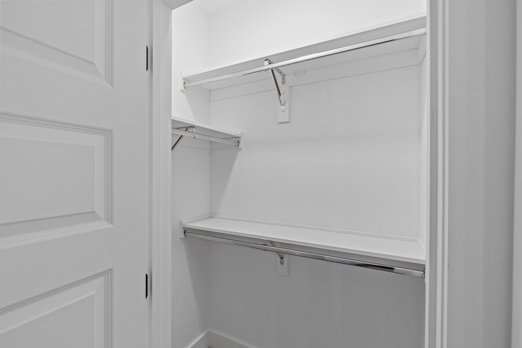 A white closet with a shelf and a door.