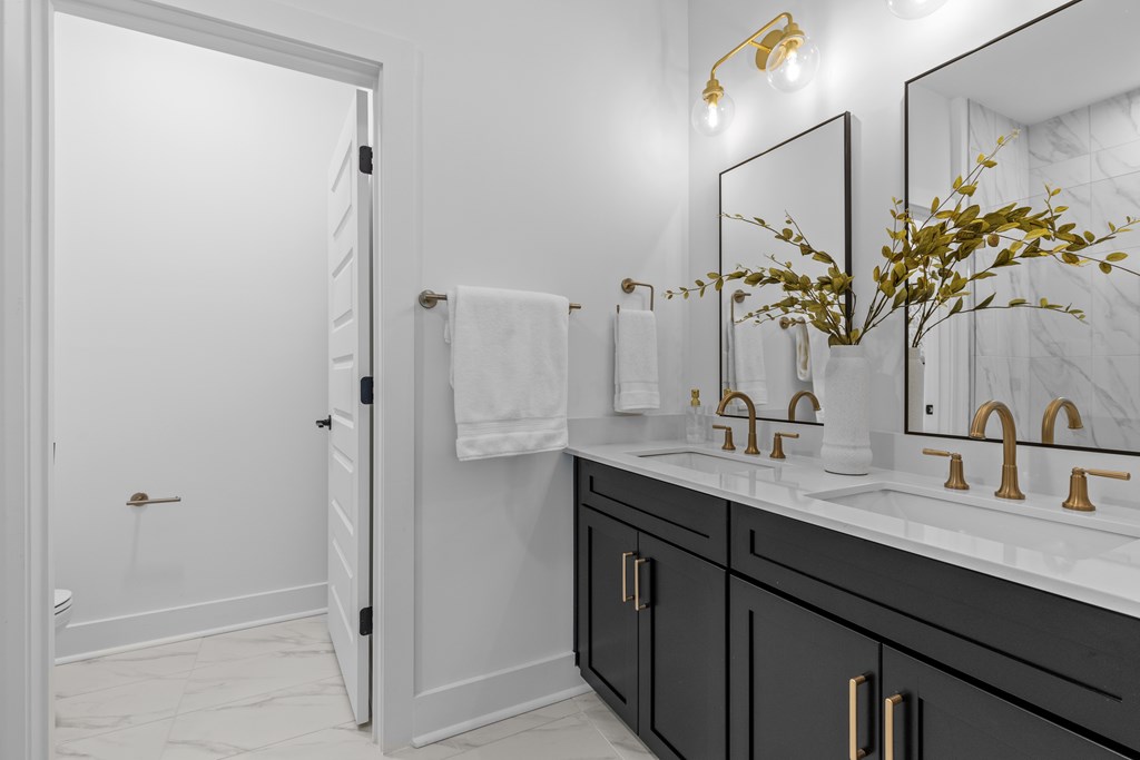 A bathroom with a white sink and gold fixtures.