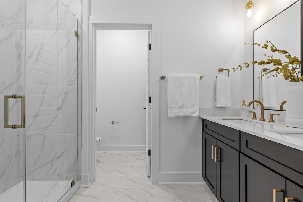 A bathroom with a marble shower and a white door.