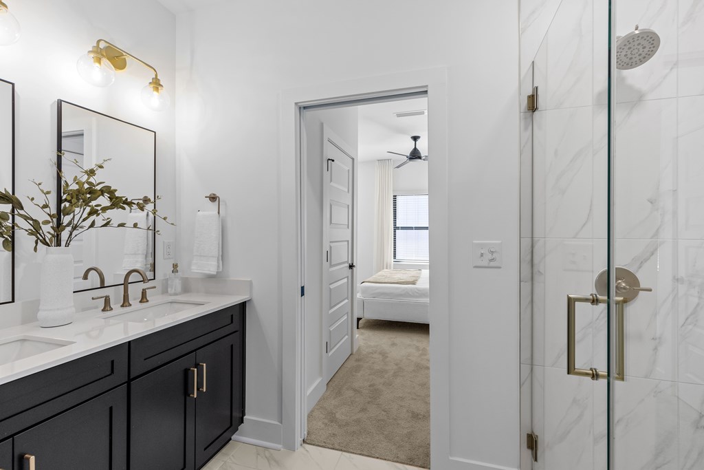 A bathroom with a marble shower door and a mirror above the sink.
