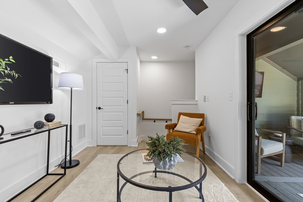 A living room with a glass table and a yellow chair.