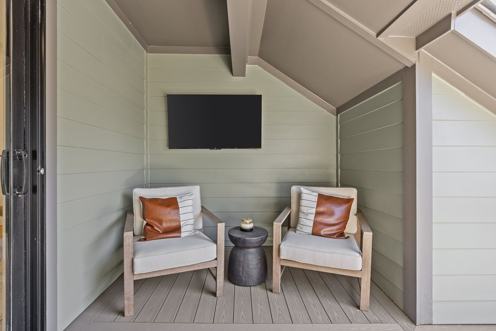 A small balcony with two chairs and a table.