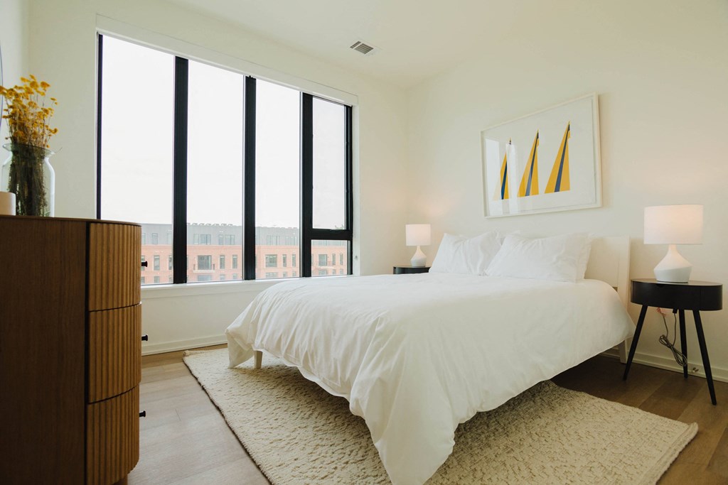 a bedroom with a large bed and large windows