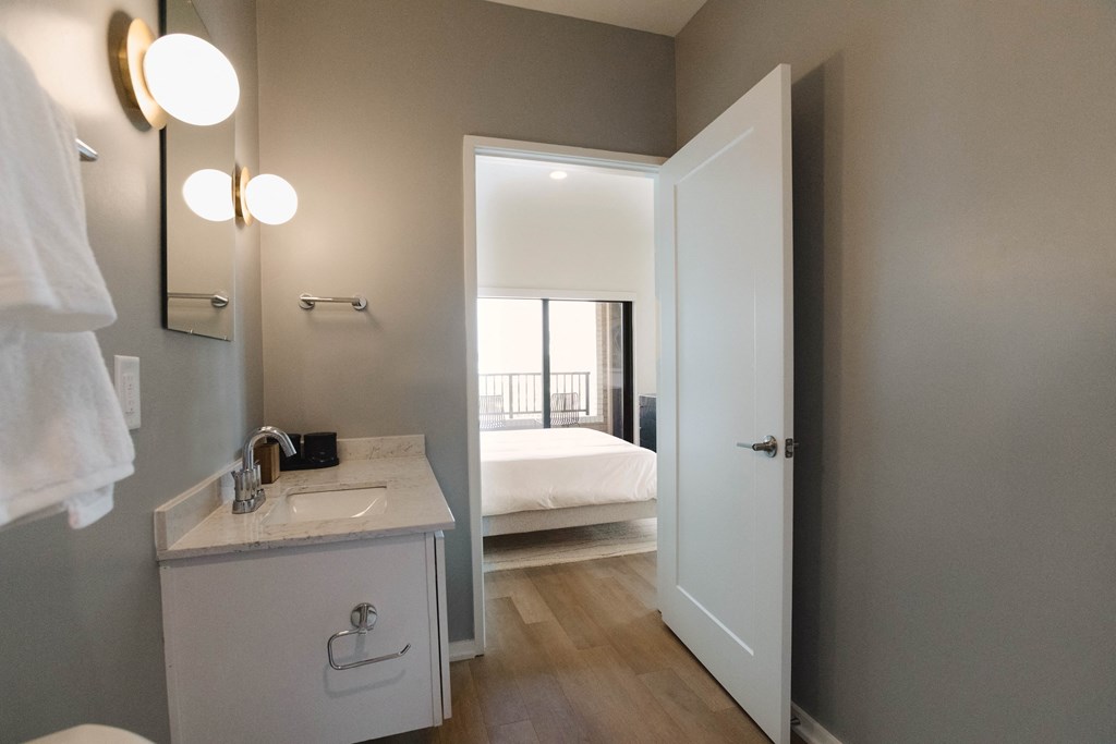 a bathroom with a white sink and a door to a bedroom