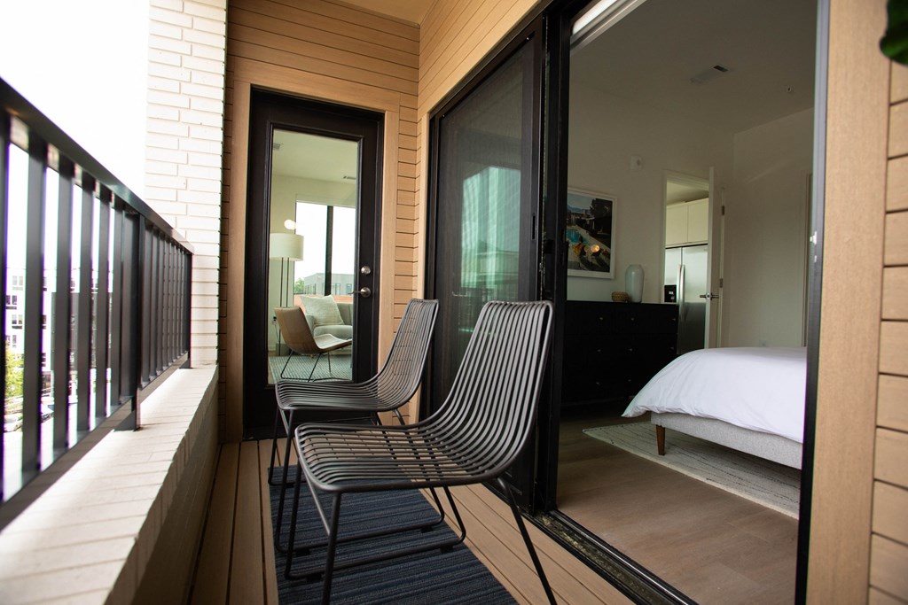 a bedroom with a bed and two chairs on a balcony