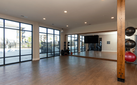 A gym with a wooden floor and a large mirror on the wall.