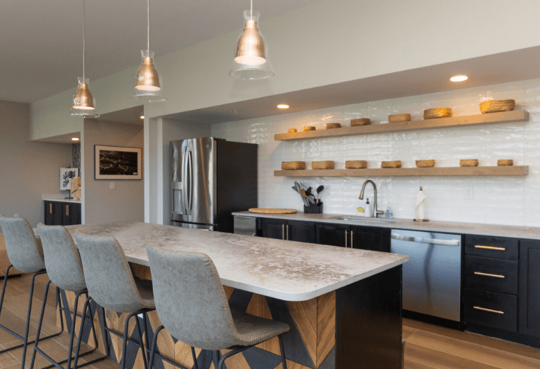 A modern kitchen with a large island and grey chairs.