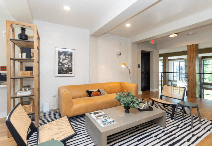 A living room with a yellow sofa and a black and white rug.