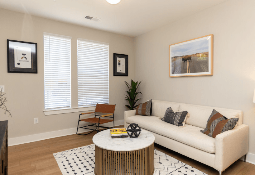 A living room with a white couch, a coffee table, and a painting on the wall.