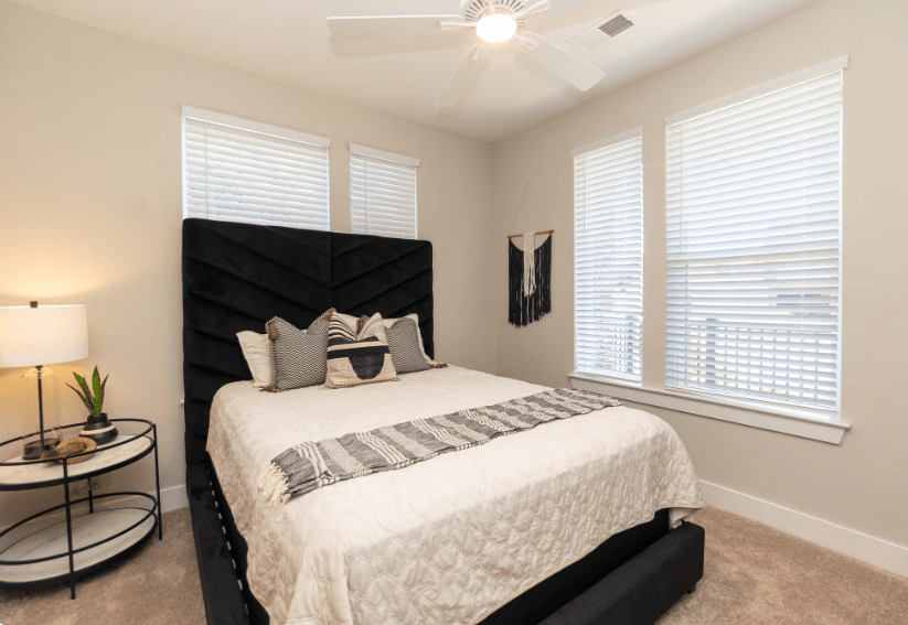 A bedroom with a large bed and a ceiling fan.