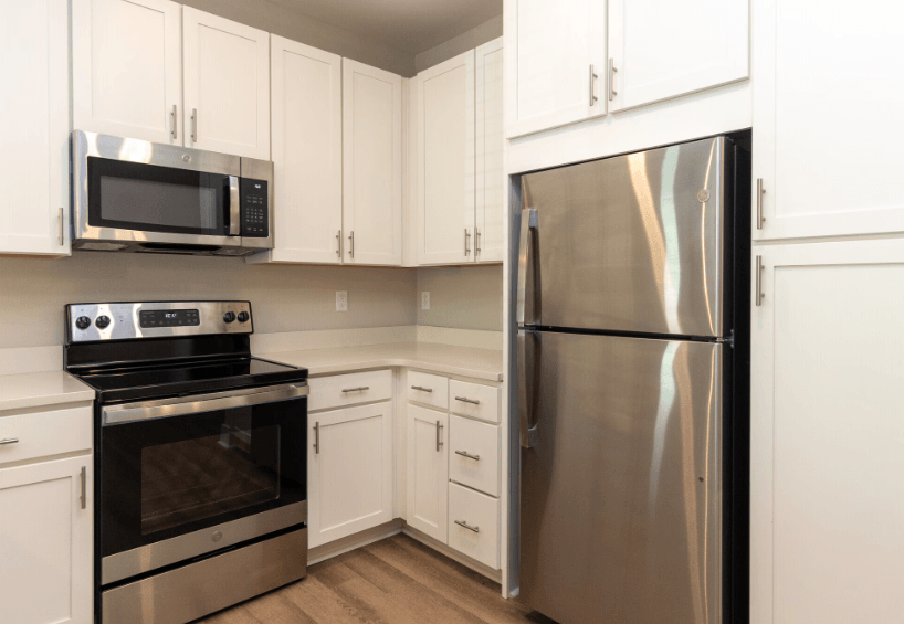 A modern kitchen with a stainless steel refrigerator, black oven, and microwave.