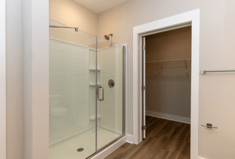 A bathroom with a walk-in shower and a door leading to another room.