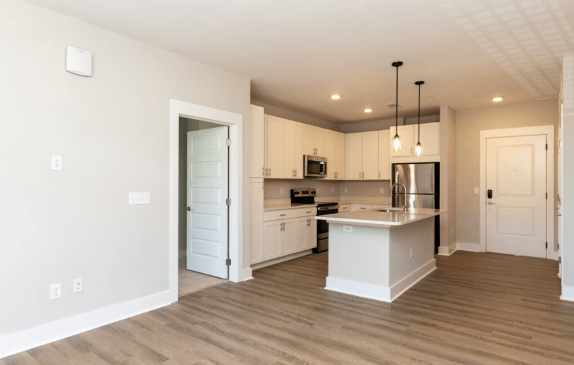 A modern kitchen with wooden floors and white cabinetry.