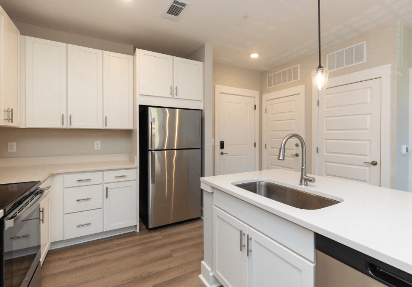 A kitchen with white cabinets and a stainless steel refrigerator.