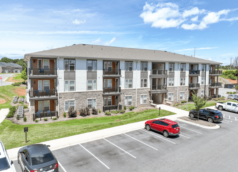 A large apartment complex with a parking lot in front.