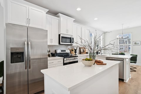 A modern kitchen with a stainless steel refrigerator and white cabinets.