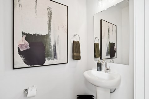 A bathroom with a white sink and a large abstract painting above it.