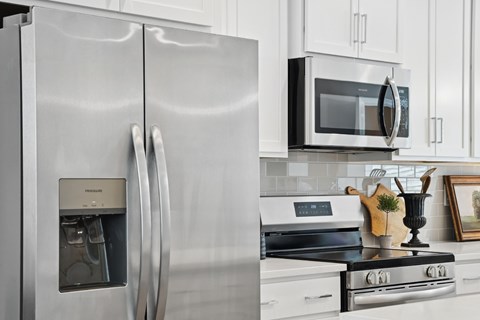 A modern kitchen with a stainless steel refrigerator and a black microwave above the stove.
