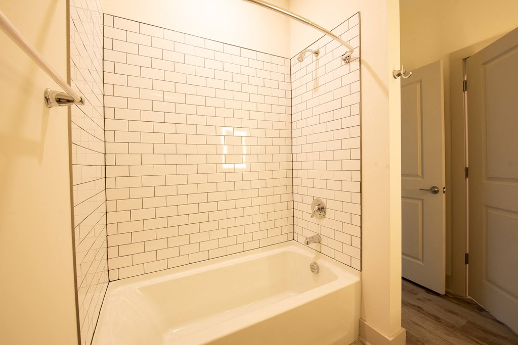 a white tiled bathroom with a tub and shower