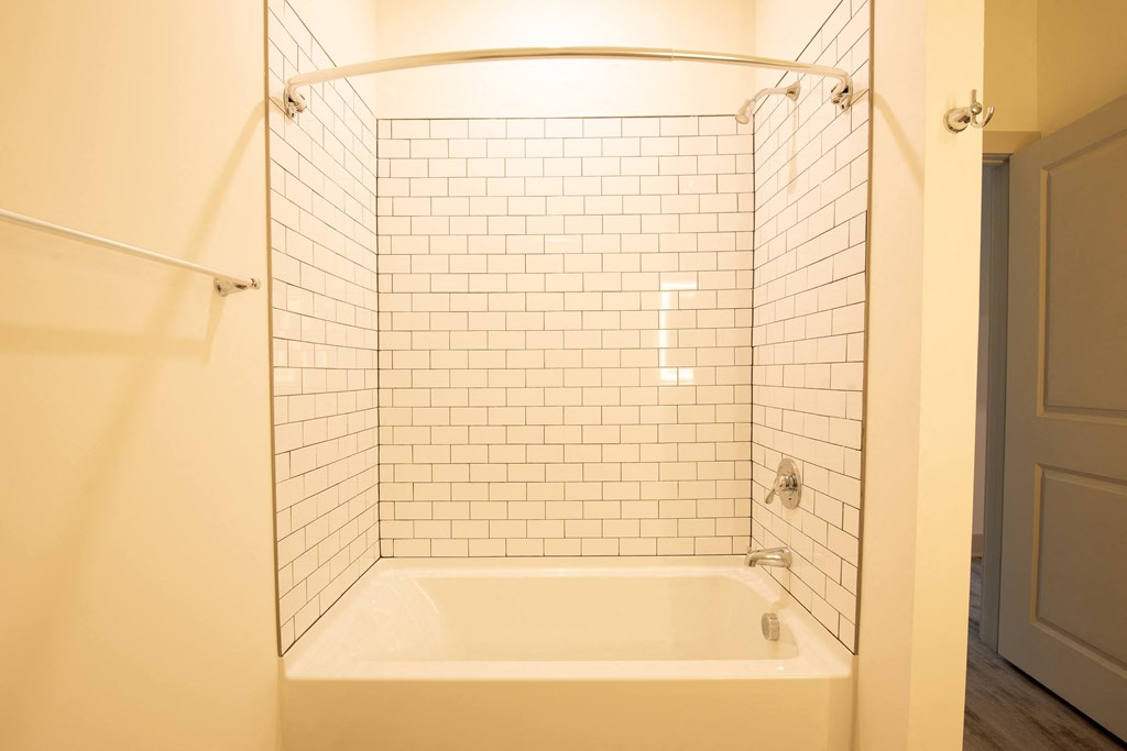 a bathroom with a tub and a shower with white tiles