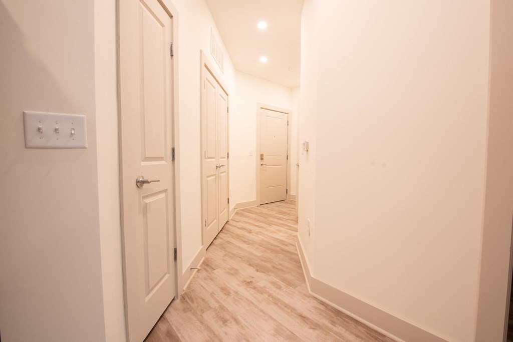 a hallway with white closets and doors and a wood floor