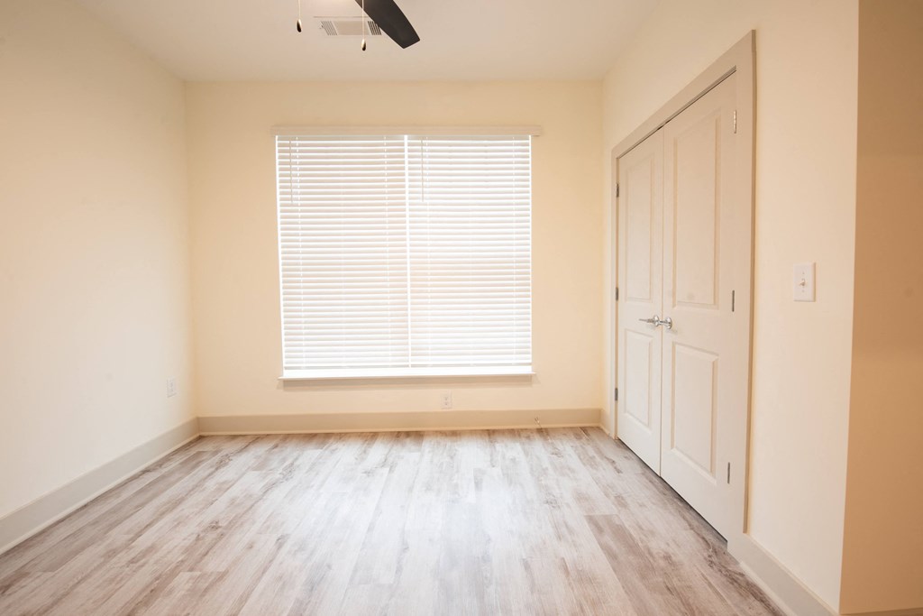 an empty room with wood floors and a window and a white door