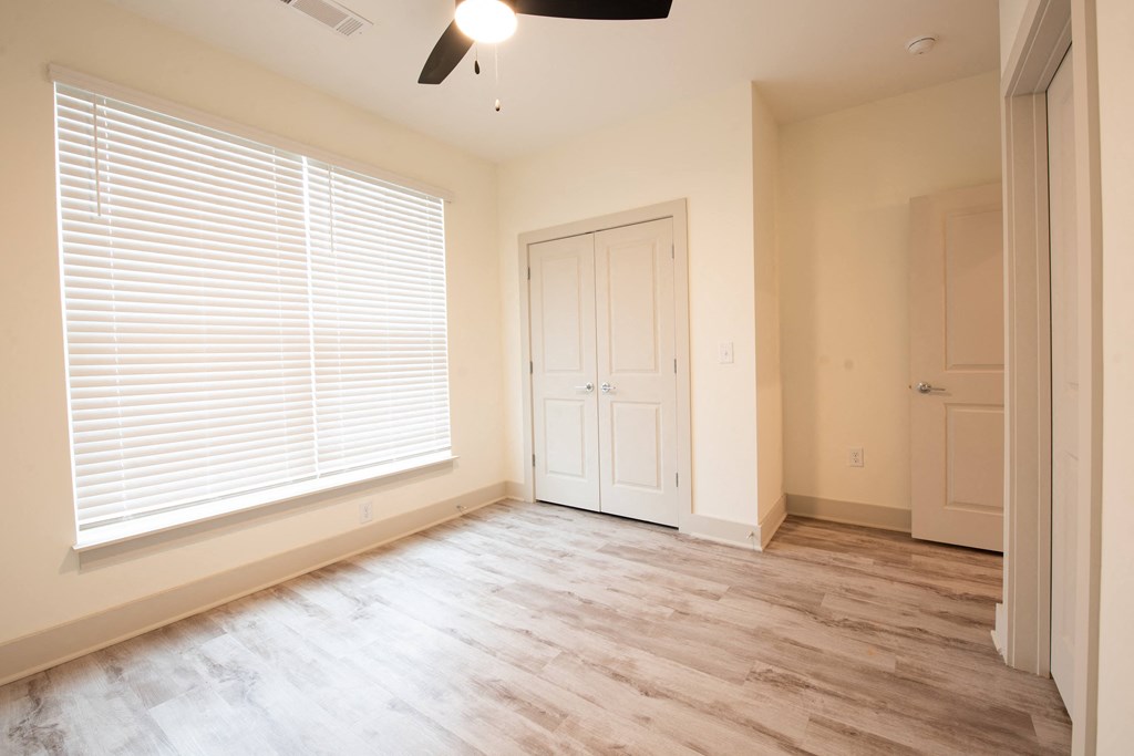 an empty living room with a large window and wood floors