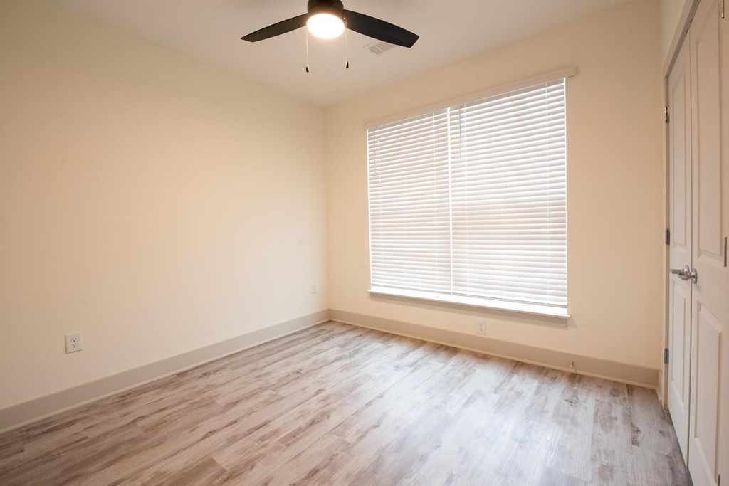 an empty living room with wood floors and a large window