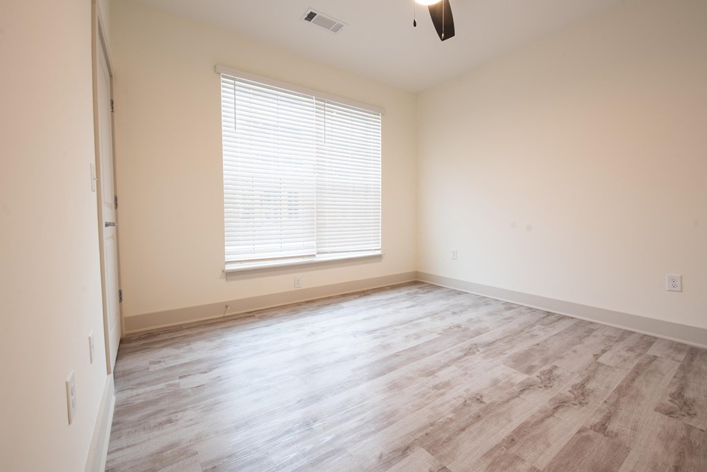 an empty bedroom with wood floors and a window