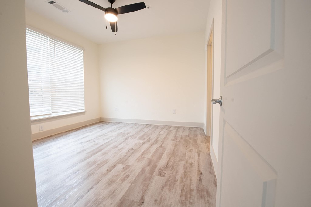 an empty bedroom with wood floors and a ceiling fan