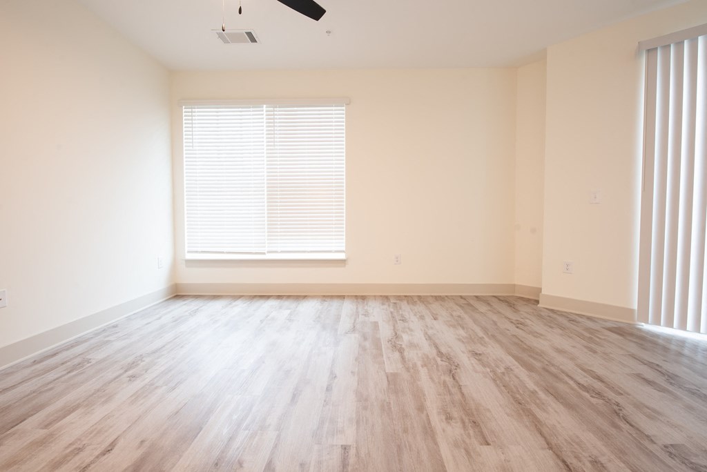 an empty living room with wood floors and a window
